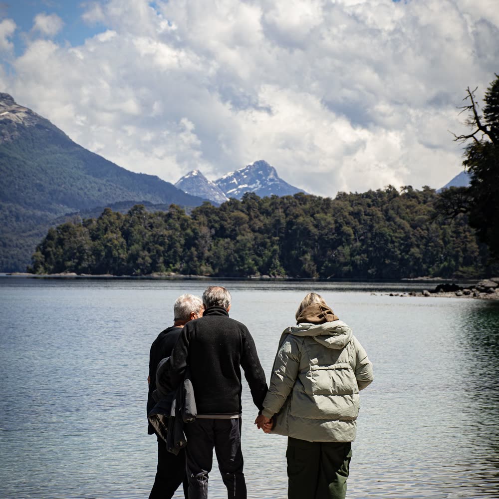 Adultos mayores caminando junto a un lago del sur
