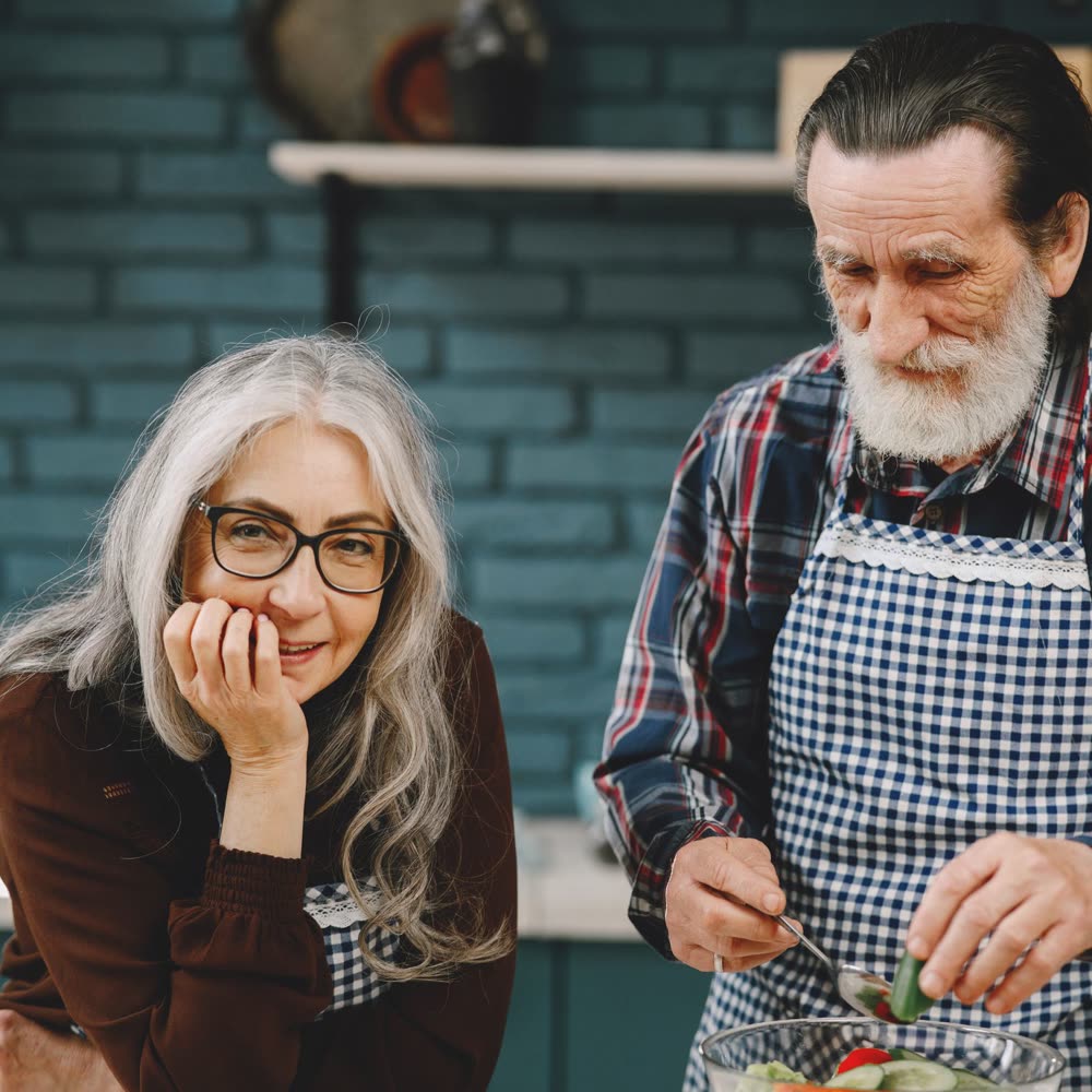 Pareja de adultos mayores preparando una ensalada